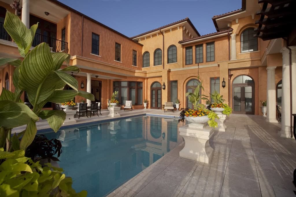 Courtyard pool enclosed by a Mediterranean-style home with arched windows