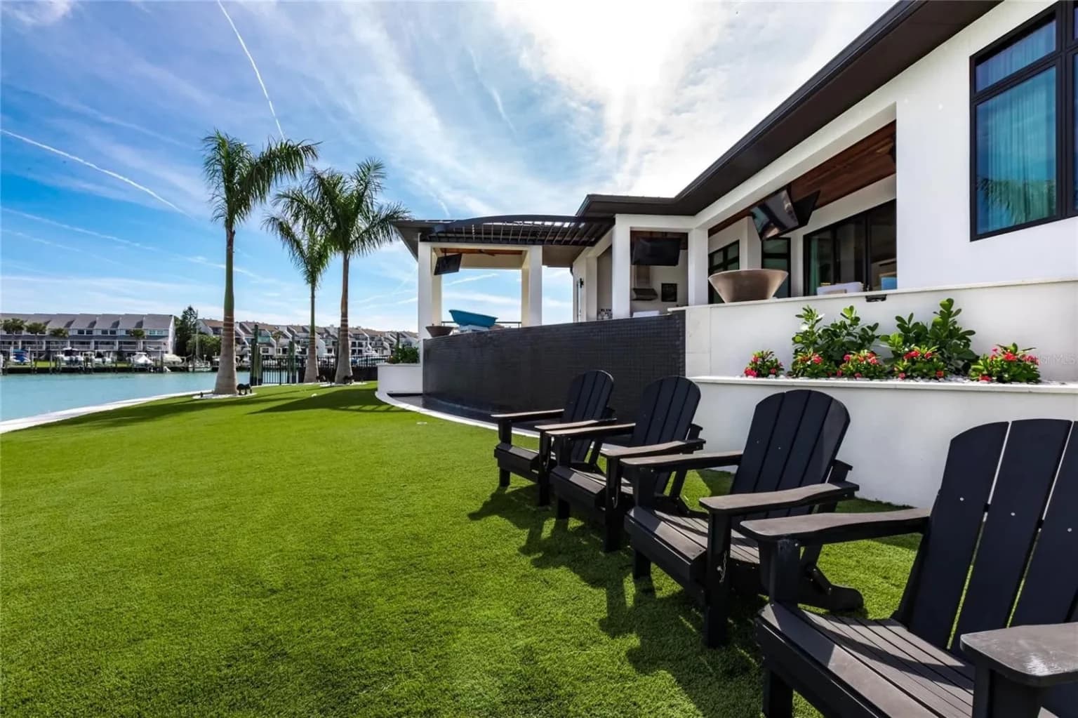 Waterfront lawn and lanai with Adirondack chairs facing a marina