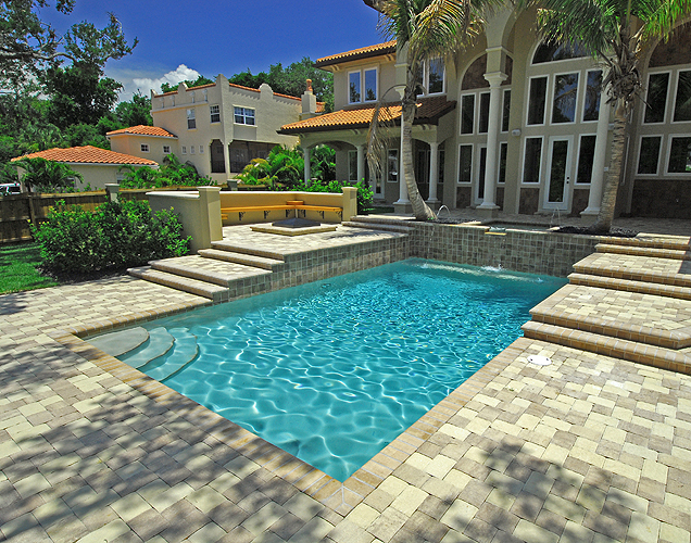 Multi-level pool deck surrounds a rectangular swimming pool in a beautiful St. Pete Beach backyard